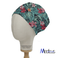 A Medicus Scrub Caps mannequin models the Hawaiian Shirt Floral Palms Scrub Cap, featuring tropical green leaves and red hibiscus flowers on a dark background.