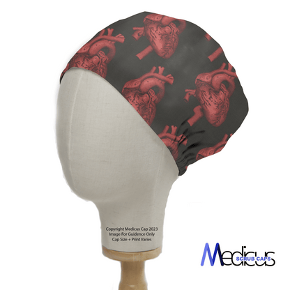 A mannequin head wears the Heart 3D On Black Scrub Cap by Medicus Scrub Caps, featuring red anatomical hearts on black fabric for a bold medical-themed design.