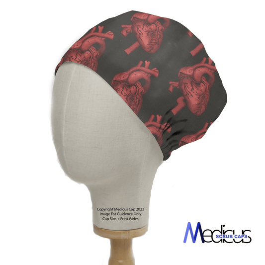 A mannequin head wears the Heart 3D On Black Scrub Cap by Medicus Scrub Caps, featuring red anatomical hearts on black fabric for a bold medical-themed design.