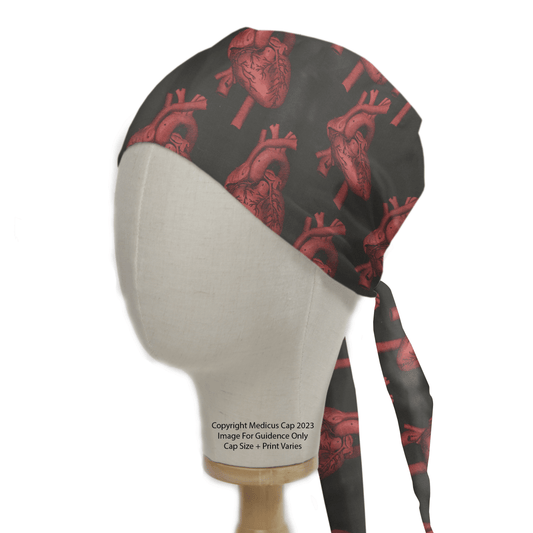 A mannequin head wearing a Heart 3D On Black Scrub Cap by Medicus Scrub Caps, featuring red anatomical hearts on black fabric, tied at the back.