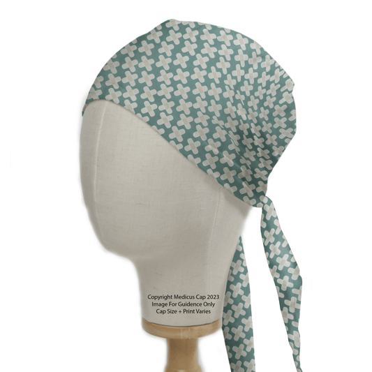 A head mannequin models the Hospital Plasters Scrub Cap by Medicus Scrub Caps, showcasing a light blue and white pattern with a cross design. Perfect for healthcare professionals, it is reusable with a tied knot at the back and displays copyright and sizing info on the mannequin.