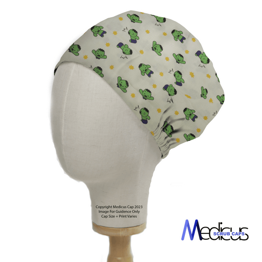 A mannequin head displays a green Hulk Smash Kawaii Superhero Scrub Cap by Medicus Scrub Caps, featuring a fun frog and blue flower pattern. Its fitted, gathered at the back, ideal for medical professionals who prefer reusable caps, with the logo in the bottom right corner.