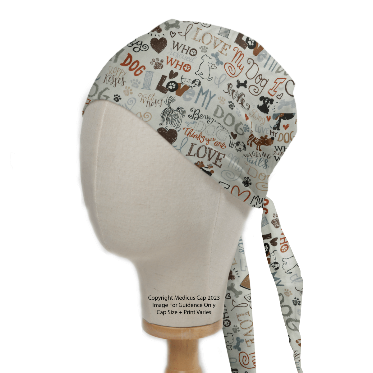 The I Love My Dogs Scrub Cap by Medicus Scrub Caps is perfect for veterinary professionals. This reusable cap, displayed on a mannequin head, showcases dog-themed prints with phrases like Woof in brown and gray, featuring ties that elegantly drape down the back.