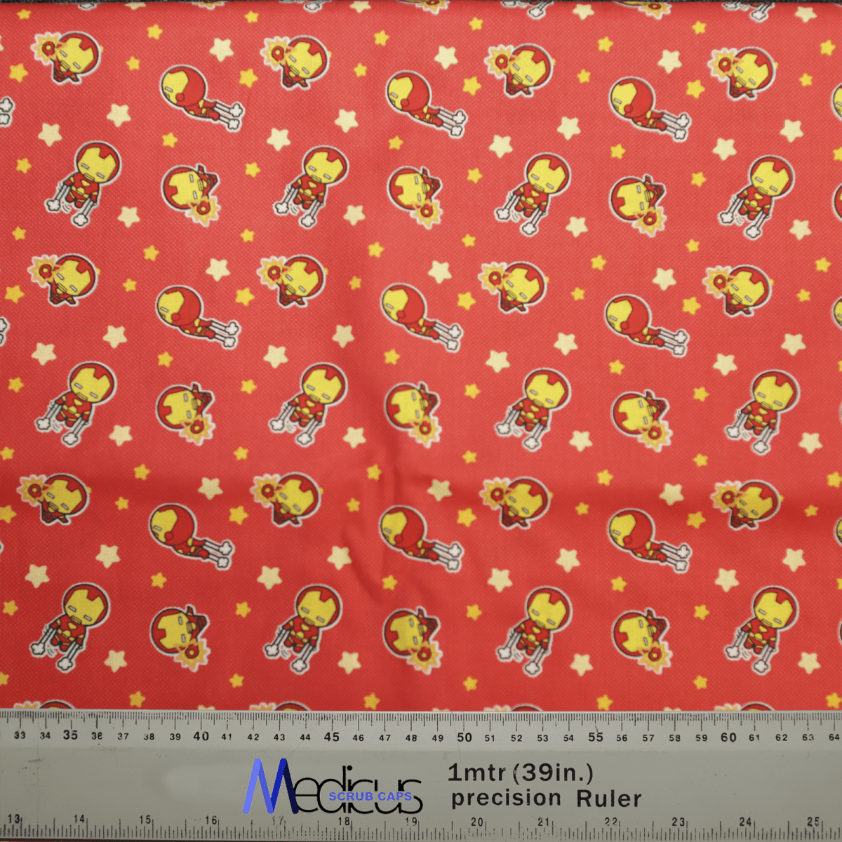 The Medicus Scrub Caps Iron Man Cartoon Kawaii Scrub Cap showcases a red fabric with adorable Iron Man motifs in vibrant red and yellow suits with helmets, accented by charming yellow stars. It includes a ruler in centimeters and inches, perfect for sustainable crafting.