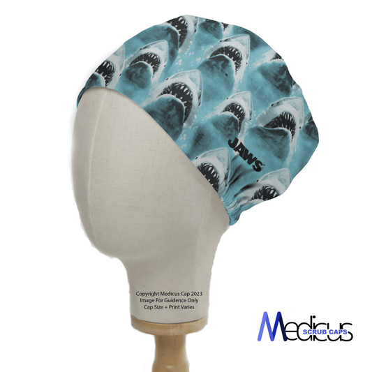 The mannequin head displays the Jaws Scrub Cap, highlighted by a repeating shark design and JAWS. Ethically sourced by Medicus Scrub Caps, it contrasts against a white background with the brand logo at the bottom right.