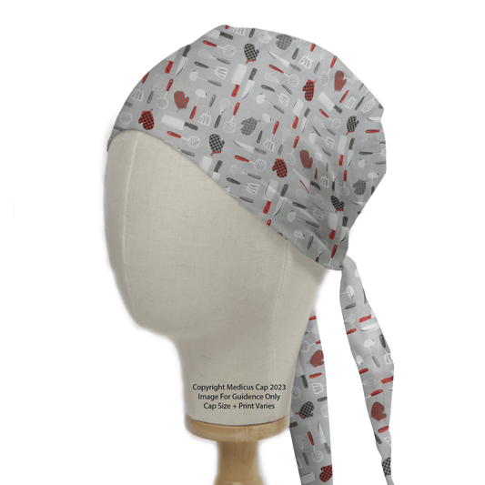 Displayed on a mannequin head, the Medicus Scrub Caps gray Kitchen Knives Scrub Cap features a utensil pattern in black, red, and white. Designed for sustainability, it offers a tied back for an adjustable fit.