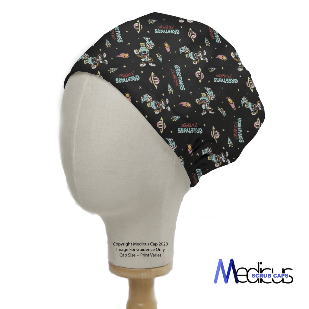 A mannequin head models a black Medicus Scrub Caps Looney Tunes Marvin The Martian Scrub Cap, showcasing space-themed illustrations like astronauts, planets, and the word GEGENS. The caps side view displays logos and copyright text.