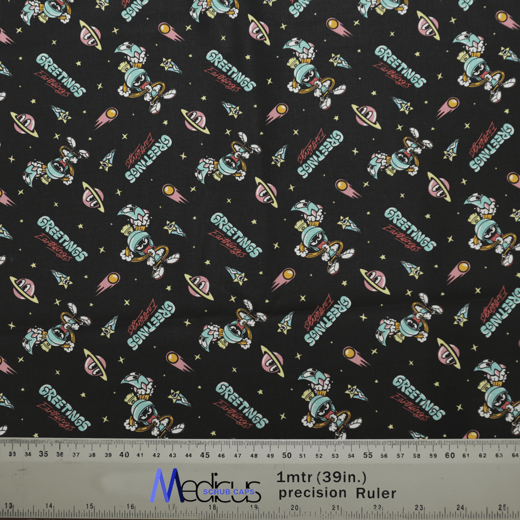 Looney Tunes Marvin the Martian Scrub Cap by Medicus Scrub Caps features Greetings Earthling and UFO designs on black, with rockets, stars, and planets. A 1-meter ruler is visible at the bottom.