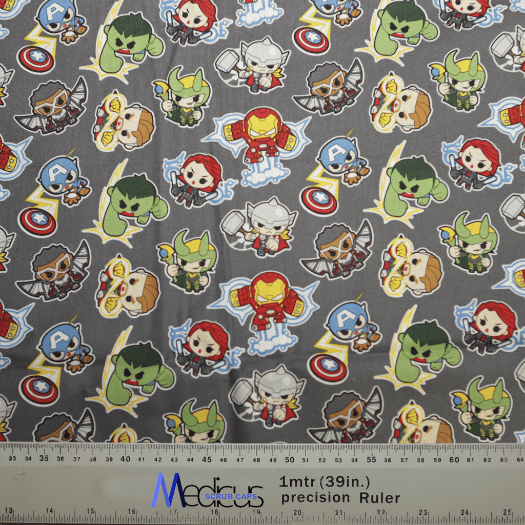 Marvel Avengers Cartoon Fight #2 Superhero Scrub Cap by Medicus Scrub Caps features patterned fabric with superhero characters, symbols on gray background, and Marvel Avengers in costumes with capes and masks. Ideal for honoring healthcare heroes. Includes measurement markings at the bottom.