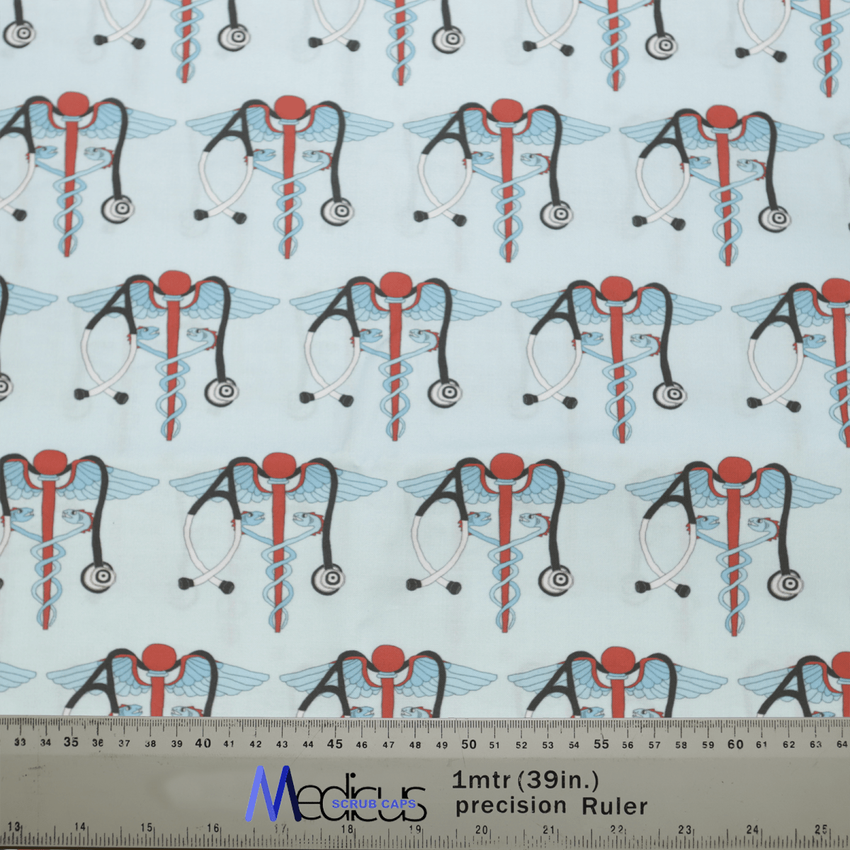 The patterned fabric includes medical snake caduceus symbols with wings, red circles, stethoscopes, and intertwined blue and red rods on a light background. Perfect for the Medicus Scrub Caps Medical Snake Caduceus Logo Blue USA Scrub Cap. Includes a one-meter ruler in centimeters and inches for scale.