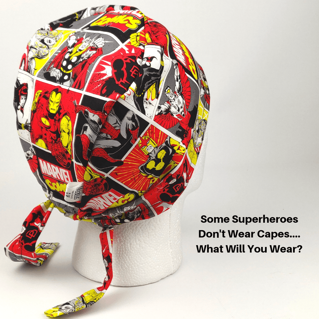 A mannequin head wears a vibrant Medicus Scrub Cap with superhero illustrations in red, yellow, and black. Beside it reads, Some Superheroes Don’t Wear Capes... What Will You Wear? Highlighting sustainability, these hypoallergenic caps are reusable. Available via Medicus Scrub Cap Gift Card.