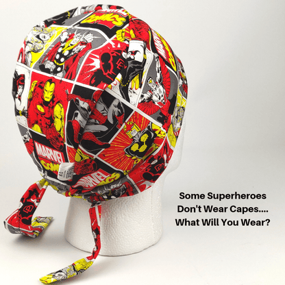 A mannequin head wears a vibrant Medicus Scrub Cap with superhero illustrations in red, yellow, and black. Beside it reads, Some Superheroes Don’t Wear Capes... What Will You Wear? Highlighting sustainability, these hypoallergenic caps are reusable. Available via Medicus Scrub Cap Gift Card.