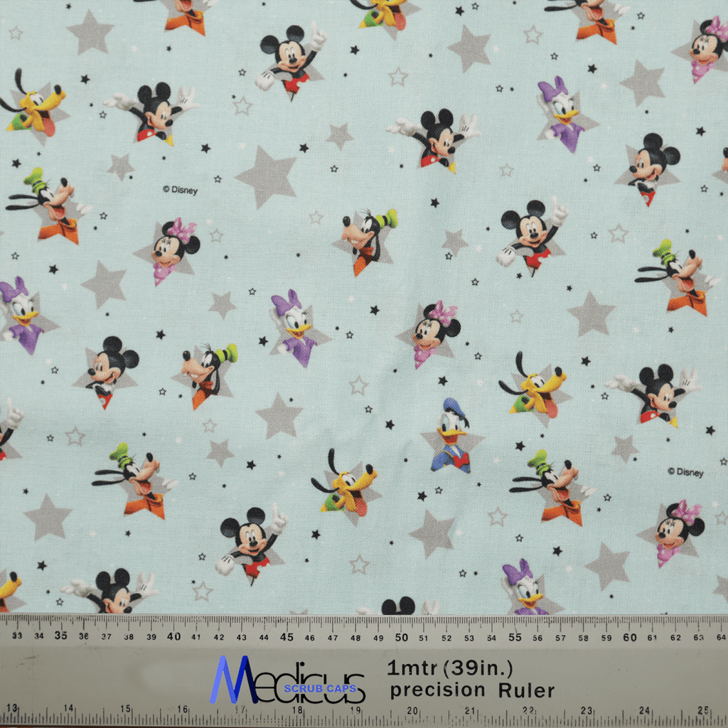 Mickey + Friends Blue Grey Stars fabric, from Medicus Scrub Caps, showcases Mickey & Friends with stars on a light blue background, ideal for crafting healthcare attire like a scrub cap. A ruler at the bottom provides scale in inches and centimeters.