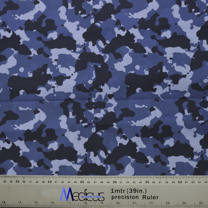 The fabric features a blue, black, gray, and white military camouflage pattern with a ruler marked in centimeters and inches at the bottom for scale. The length of 1 meter (39 inches) is shown. Ideal for crafting the Medicus Scrub Caps Military Camouflage Navy Scrub Cap.
