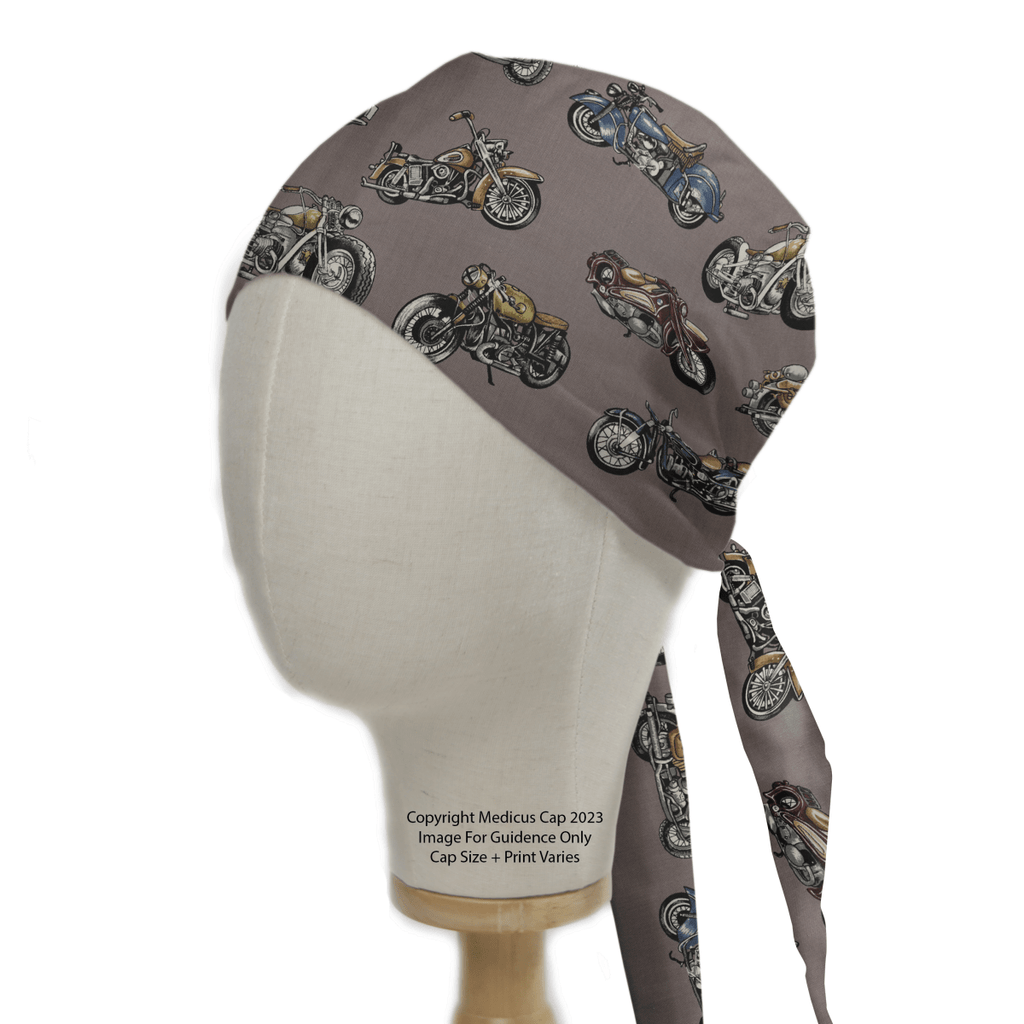 A mannequin head displays the eco-friendly Motorbike Vintage 1950 Scrub Cap by Medicus Scrub Caps, featuring classic motorcycle illustrations on a gray background. The high-quality cap ties at the back and rests on a sturdy wooden base, ideal for motorcycle enthusiasts.