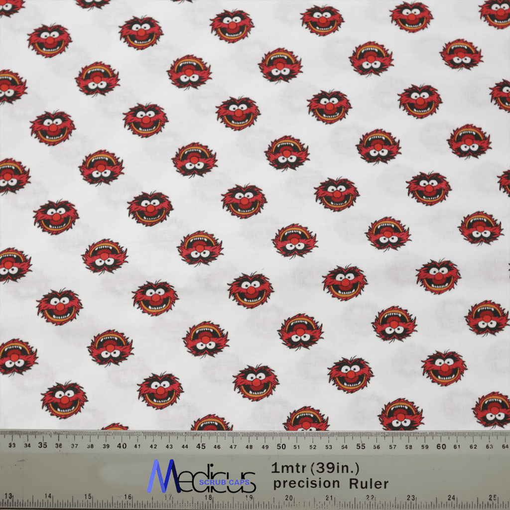 The Medicus Scrub Caps Muppets Animal Toss showcases small red monster faces with wild hair and wide eyes on a white backdrop. Ideal for adding fun to medical attire, this design includes a ruler at the bottom showing measurements in meters and inches for comfort.