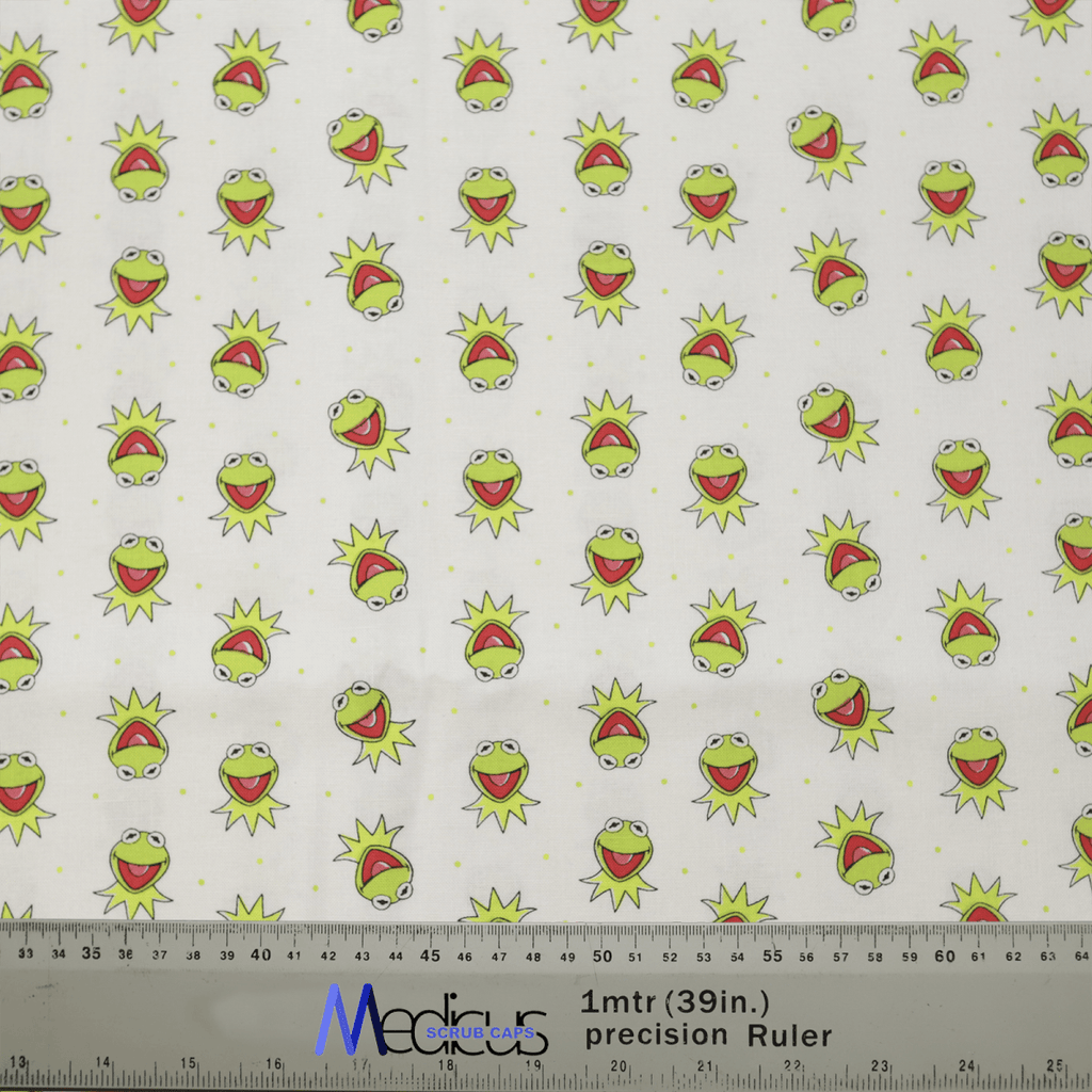 Introducing the eco-friendly Medicus Scrub Caps Muppets Kermit Toss Scrub Cap, crafted from white fabric with a playful pattern of cartoonish green frog faces featuring wide-open mouths and surprised expressions. The design is evenly spaced, with measures in inches and centimeters at the bottom.