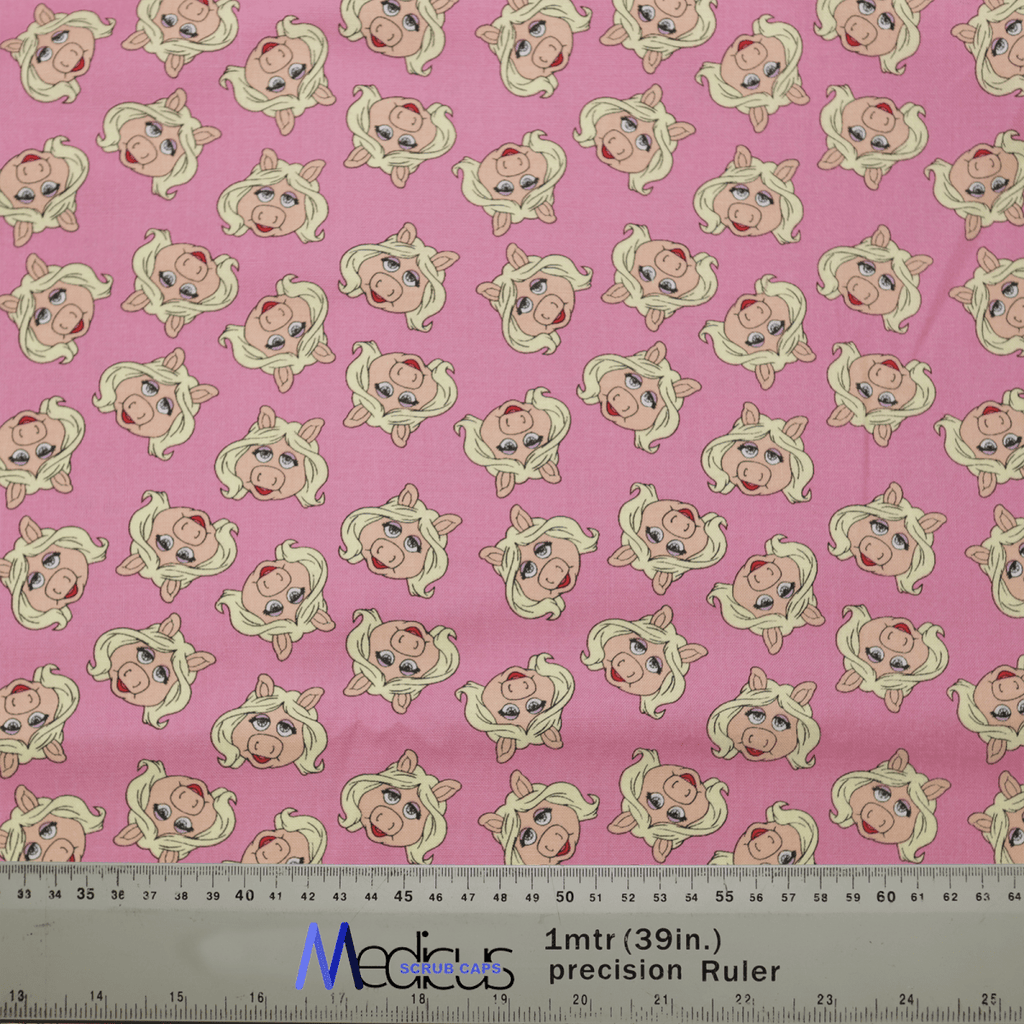 The Muppets Miss Piggy Toss Scrub Cap by Medicus Scrub Caps features a pink fabric with cartoon Miss Piggy sporting blonde hair and pearl earrings. Its perfect for healthcare professionals seeking style in the medical field, complete with a ruler for easy measurement.