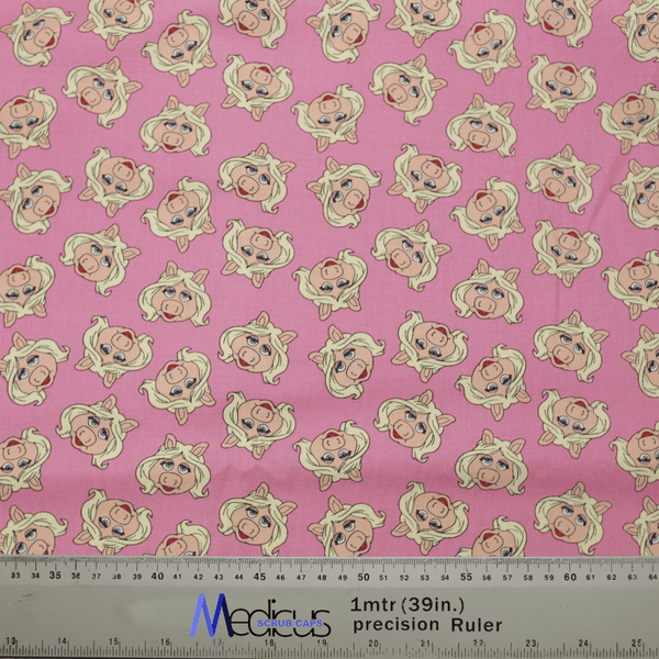 The Muppets Miss Piggy Toss Scrub Cap by Medicus Scrub Caps features a pink fabric with cartoon Miss Piggy sporting blonde hair and pearl earrings. Its perfect for healthcare professionals seeking style in the medical field, complete with a ruler for easy measurement.