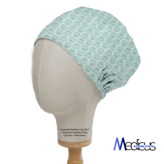 The mannequin head displays an Organic Owls Blue Scrub Cap by Medicus Scrub Caps, featuring a light green base with a hexagonal pattern and subtle red dots. Positioned on a white background, this reusable cap merges functionality with eco-conscious style.