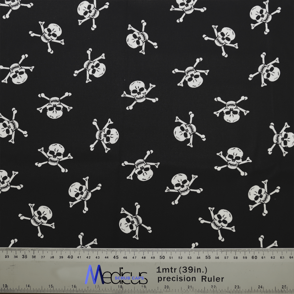 The Medicus Scrub Caps Pirate Skulls Classic Black + White features a black fabric with white skull and crossbones, ideal for crafting a comfortable healthcare scrub cap. The ruler at the bottom ensures precise measurement for a perfect fit.