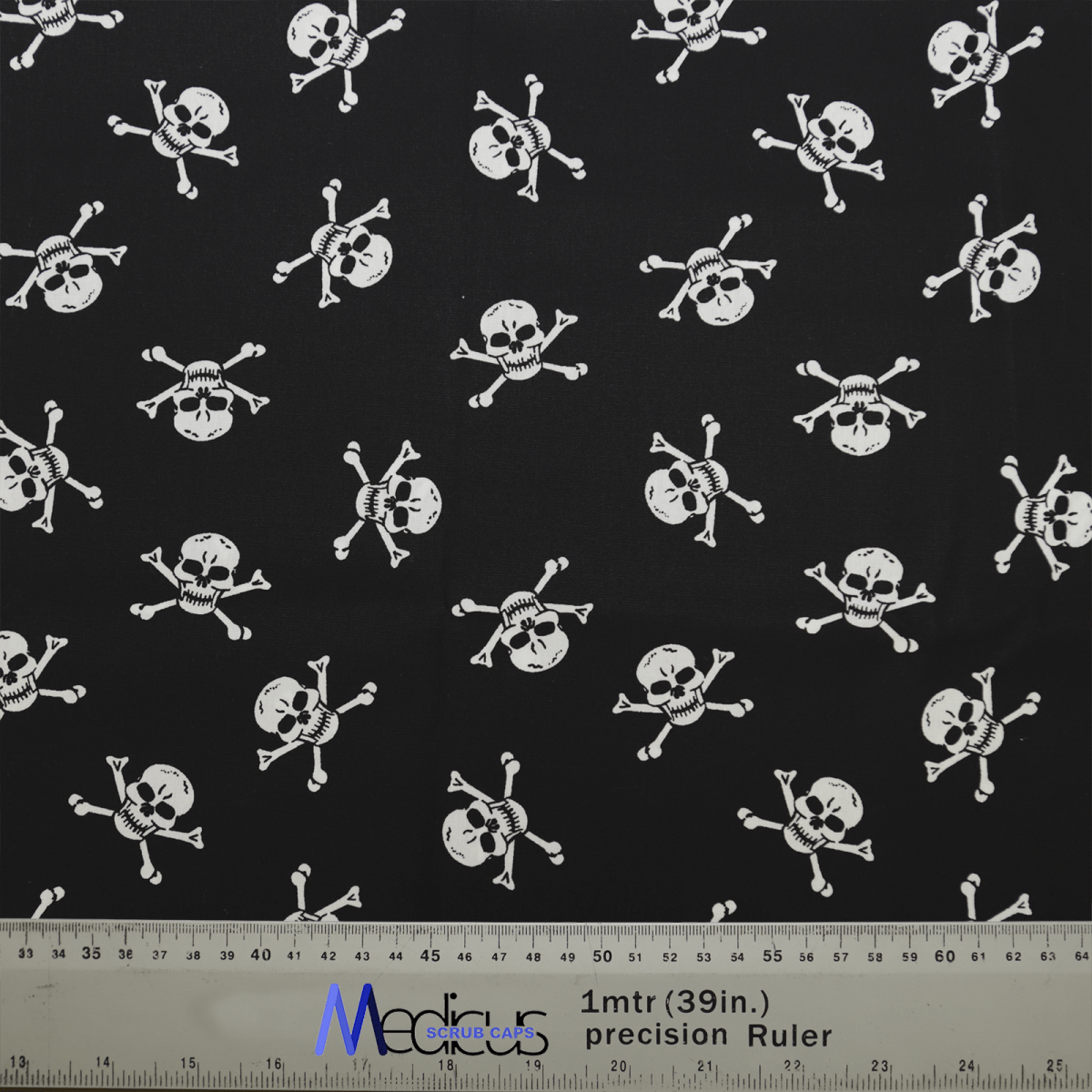 The Medicus Scrub Caps Pirate Skulls Classic Black + White features a black fabric with white skull and crossbones, ideal for crafting a comfortable healthcare scrub cap. The ruler at the bottom ensures precise measurement for a perfect fit.