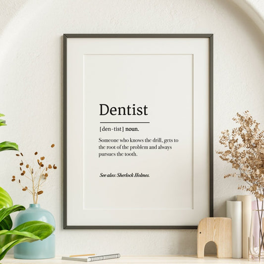 A framed Poster - Dentist Definition Poster / Digital Download humorously compares a dentist to Sherlock Holmes. Its surrounded by plants and a wooden elephant, with customization options for personal touches like adding Medicus Scrub Caps or downloading digitally.