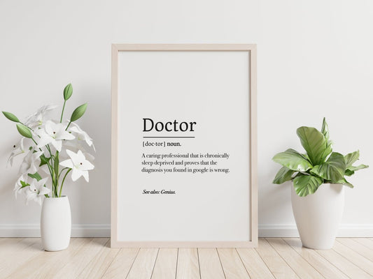 A digitally downloaded Doctor Definition Poster humorously defines a doctor as sleep deprived, complemented by a playful Medicus Scrub Cap. It is adorned with white vases, flowers, and a leafy plant on the light floor against a pale wall.