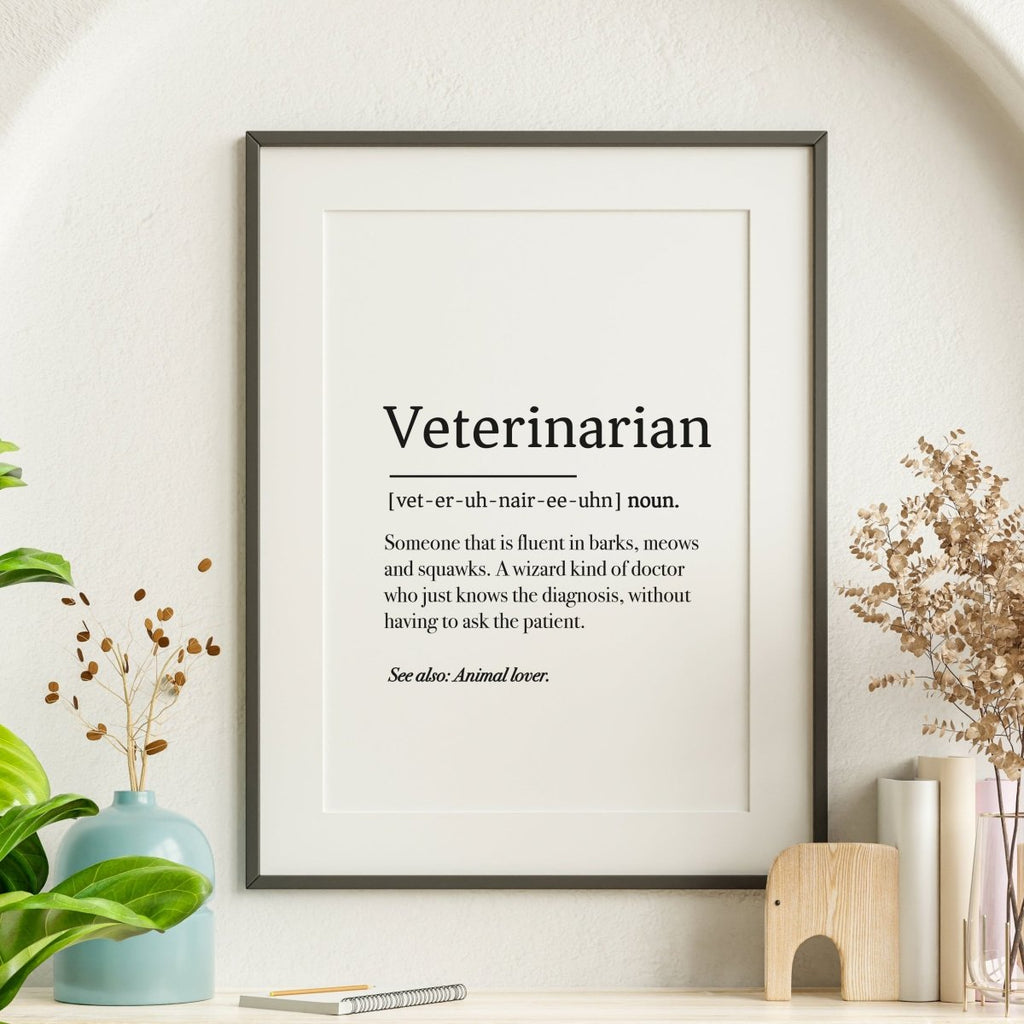 A digital downloadable file from Medicus Scrub Caps named Poster - Veterinarian Definition Poster humorously defines Veterinarian like a dictionary entry, capturing the essence of diagnosing without patient input. The print is styled among plants and decor on a shelf.