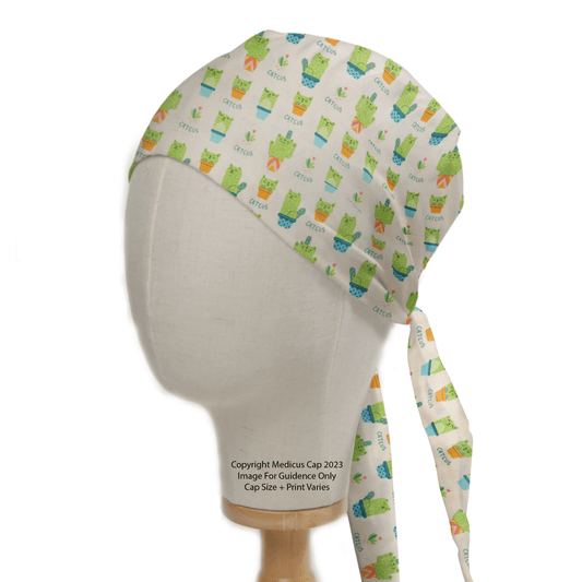 The mannequin showcases a Pun-tastic: Cat-cus Scrub Cap by Medicus Scrub Caps, a sustainable medical apparel item with a vibrant cacti-in-pots pattern on white, featuring long ties that hang gracefully.