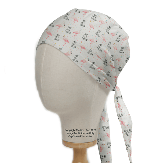 Medicus Scrub Caps Pun-tastic: Party Like A Flock Star scrub cap is showcased on a mannequin head, featuring a vibrant pink flamingo design and playful text. The white cap offers two adjustable back ties, combining style and practicality.