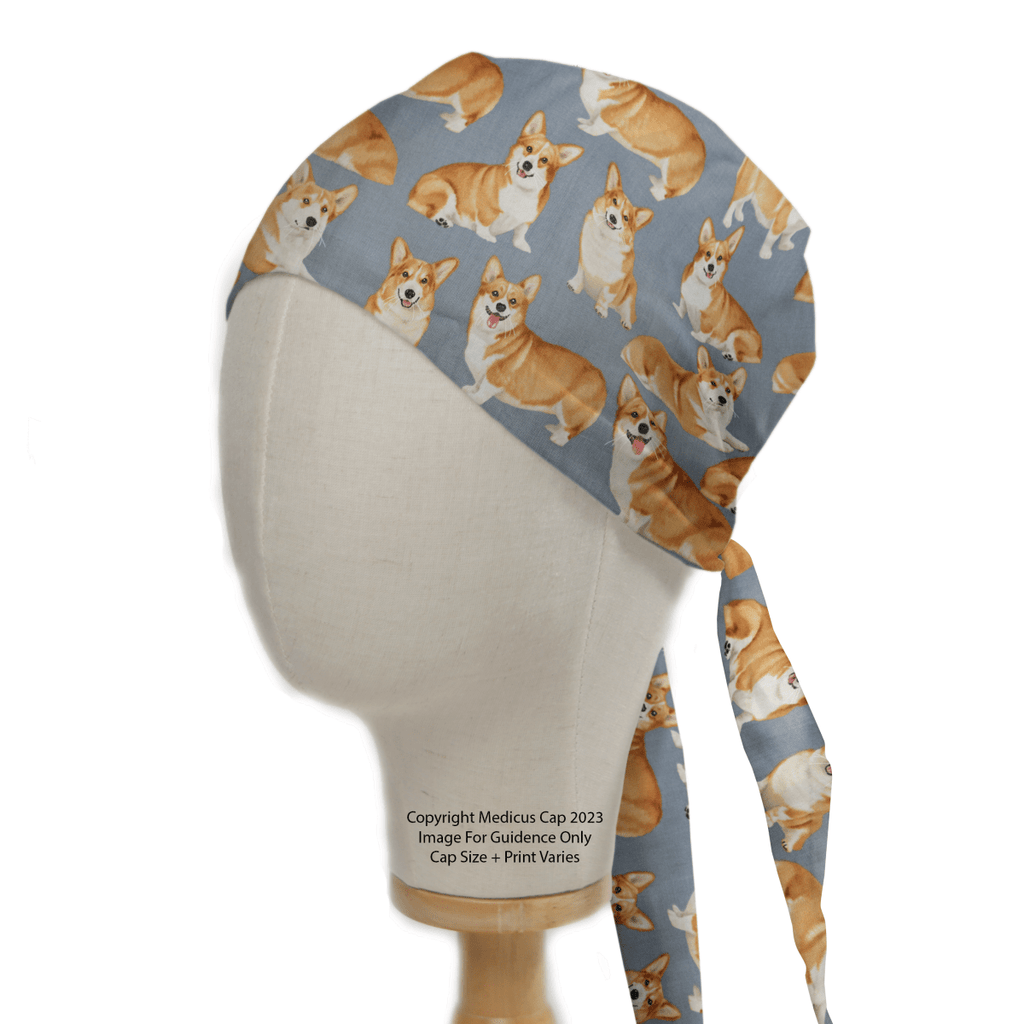 A mannequin head showcases the Medicus Royal Corgi Dogs Scrub Cap, adorned with tan and white corgis on a grayish-blue background. Ideal for eco-conscious healthcare professionals, it elegantly ties at the back and is depicted from the side.