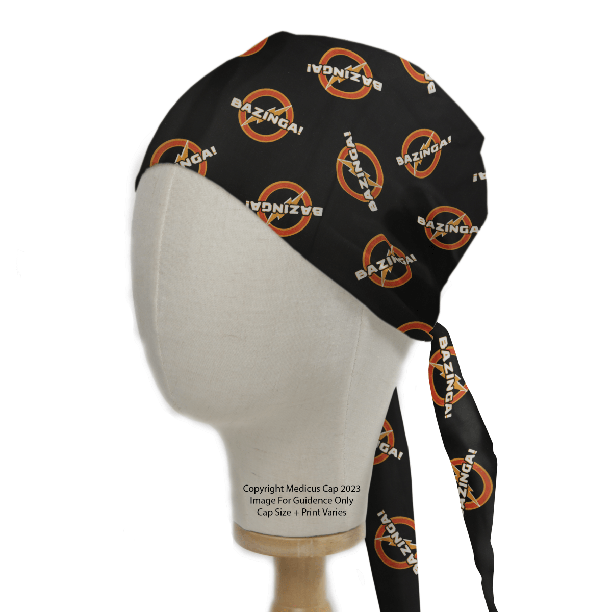 A mannequin head models a Medicus Scrub Caps eco-friendly black scrub cap adorned with a playful pattern featuring an orange circle and slash over the white and orange word BAZINGA! from Science Big Bang Theory, stylishly tied at the back.