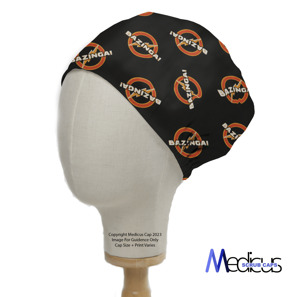 A mannequin head displays a black Medicus Scrub Caps Bazinga! scrub cap, inspired by The Big Bang Theory, featuring circular designs with an orange border on a white background.