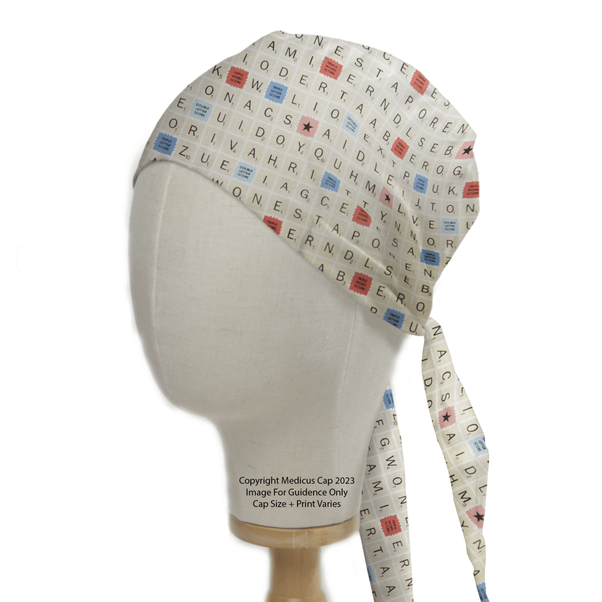 The Medicus Scrub Caps Scrabble Board Classic Vintage Scrub Cap features a crossword puzzle design with letter tiles and blue and red star illustrations, complete with long ties, perfect for word enthusiasts.
