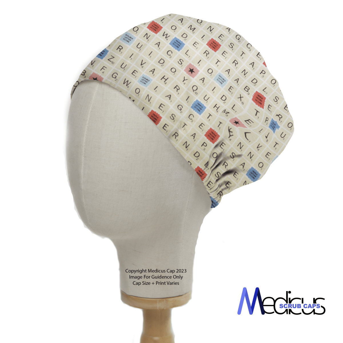 A mannequin head displays the Scrabble Board Classic Vintage Scrub Cap by Medicus Scrub Caps, featuring an off-white crossword grid design with multicolored letters, perfect for word enthusiasts. The playful print resembles a Scrabble board, with the logo elegantly on the bottom right.