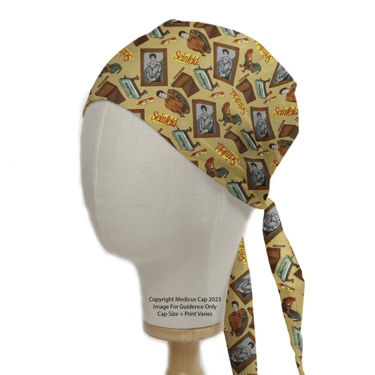 A head mannequin displays the Seinfeld Wallpaper Scrub Cap by Medicus Scrub Caps, featuring historical-themed illustrations, portraits, cartoon cats, and Schrödinger. The cap is crafted for an eco-friendly and comfortable fit with tied tails at the back.