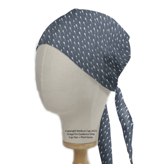 Displayed on a mannequin head is the Sperm Rush Hour Scrub Cap by Medicus Scrub Caps, honoring healthcare heroes with its dark blue fabric and whimsical small white spoon pattern, featuring a tied back band that blends functionality and style seamlessly.