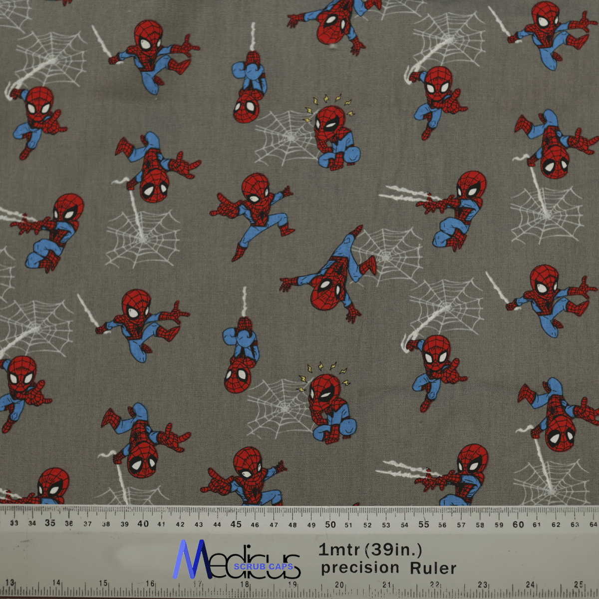 The Spiderman Kawaii On Grey Scrub Cap by Medicus Scrub Caps features small red and blue superhero illustrations swinging on a gray background. A ruler at the bottom shows length in inches and centimeters, ensuring an exceptional fit and comfort for healthcare professionals.