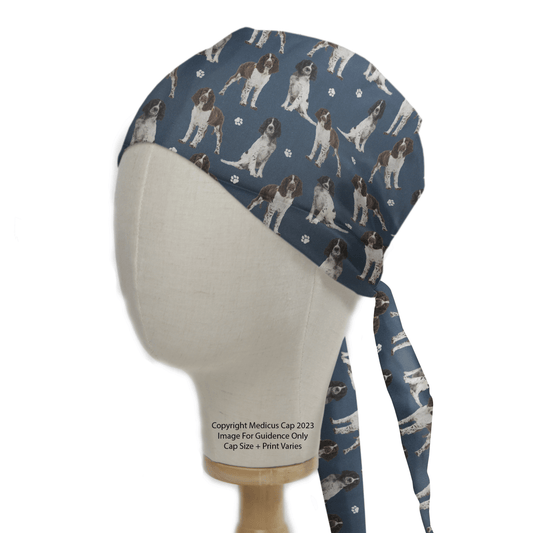 The mannequin head displays the Springer Spaniel Dogs Blue Scrub Cap by Medicus Scrub Caps, featuring dog illustrations with paw prints, tied neatly at the back.