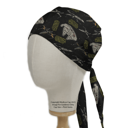 A mannequin head exhibits a Medicus Scrub Cap featuring Star Wars logos and TIE Fighters. This black, yellow-themed scrub cap ties at the back with long, elegant tails.