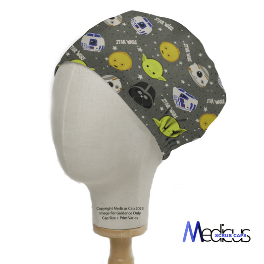 A mannequin head displays the Medicus Scrub Caps Star Wars Kawaii Heads Yoda Scrub Cap, featuring kawaii-style Baby Yoda and R2-D2 on a starry gray backdrop, completed with a cute green bow at the back.