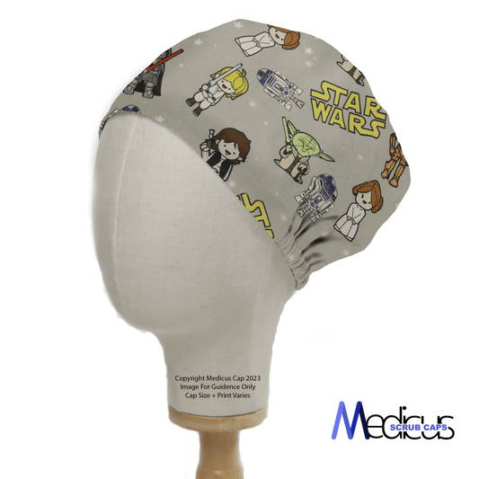 A mannequin head wears the Star Wars Original Kawaii Scrub Cap by Medicus Scrub Caps, showcasing cute cartoon characters and robots. This reusable cap is ideal for fans wanting style and functionality, with the brands logo at the bottom right.