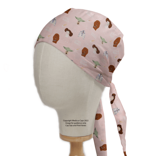 The Star Wars Pink Kawaii Scrub Cap by Medicus Scrub Caps, displayed on a mannequin head, features charming cartoon figures and spaceships. Adorned with Star Wars-themed kawaii characters and icons, it offers an adjustable fit with ties at the back as a sustainable choice.