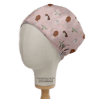 A mannequin head features the Medicus Scrub Caps Star Wars Pink Kawaii scrub cap, decorated with small green aliens, helmets, and droids. Its sustainably displayed on a wooden stand with text below.