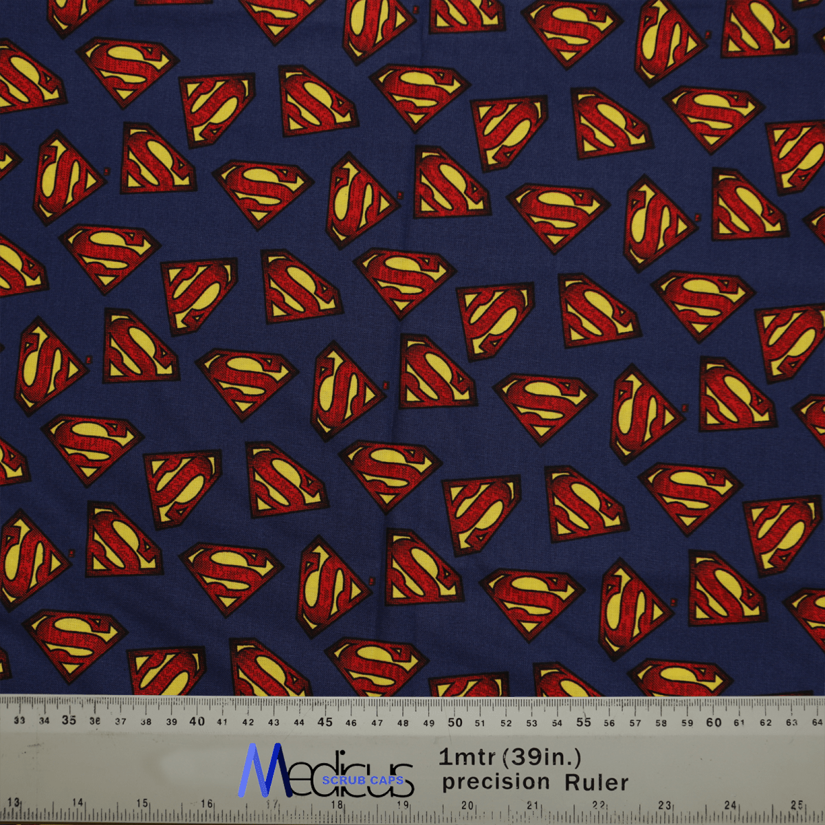 Medicus Scrub Caps eco-friendly Superman Logo On Navy Scrub Cap is designed with blue fabric showcasing red and yellow Superman logos, complete with a ruler at the bottom for measurements in centimeters and inches.