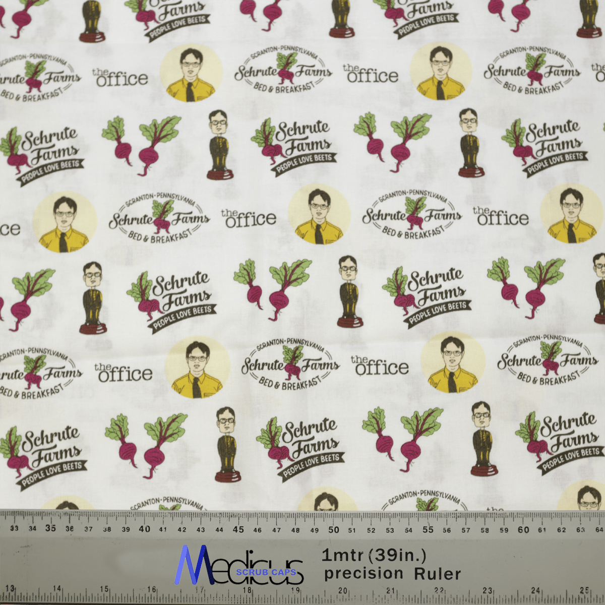 The The Office Schrute Farms Scrub Cap by Medicus Scrub Caps features cartoon characters in suits, beets, and text like “Schrute Farms Bed & Breakfast” and “The Office,” ideal for Healthcare Style enthusiasts. A ruler displays scale at the bottom.