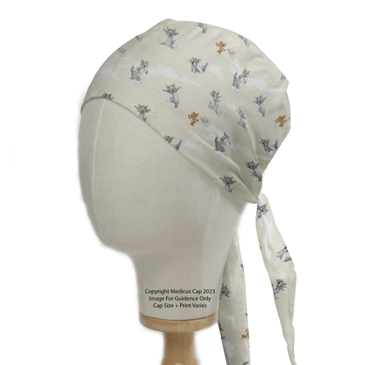 A mannequin head showcases the Tom And Jerry Clouds Beige Scrub Cap by Medicus Scrub Caps, featuring whimsical animal designs and a back tie strap, all set against a plain white background.