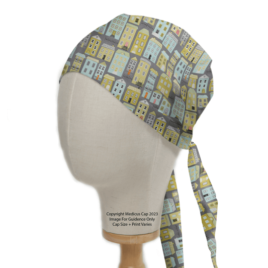 The Medicus Scrub Caps Townhouse Scrub Cap is a sustainable, reusable accessory featuring vibrant patterns of yellow, blue, and gray stylized houses. Ideal for healthcare professionals, it offers tied straps for a secure fit and is showcased on a mannequin head.