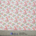 The Medicus Scrub Caps Unicorns Flower Power Scrub Cap features fabric with pink unicorns and colorful flowers on a white background, ideal for crafting. A transparent ruler marks centimeters and inches for precise cutting.